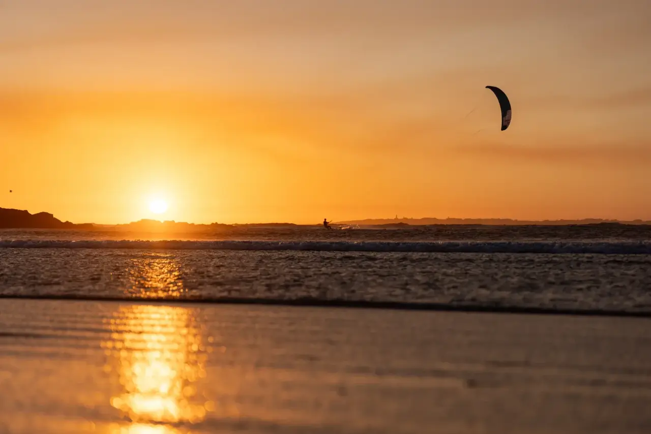 Silhouette d'un kiteur au coucher du soleil, ciel orange