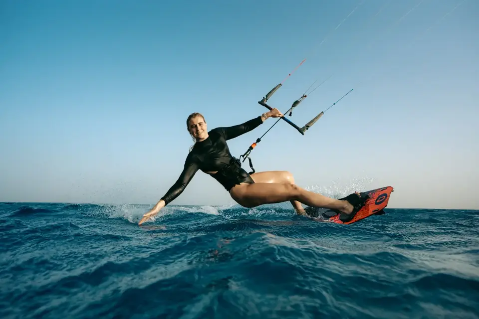 Kiteuse souriante en virage sur une mer bleu profond