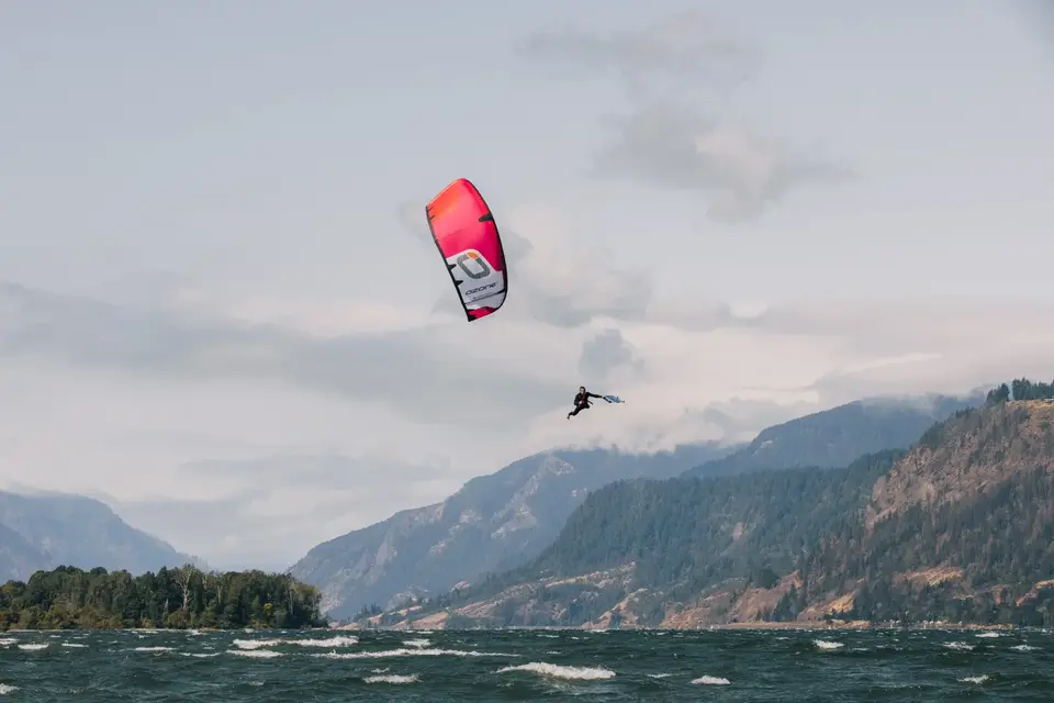 Saut de kite, aile rose, dans une gorge de montagne