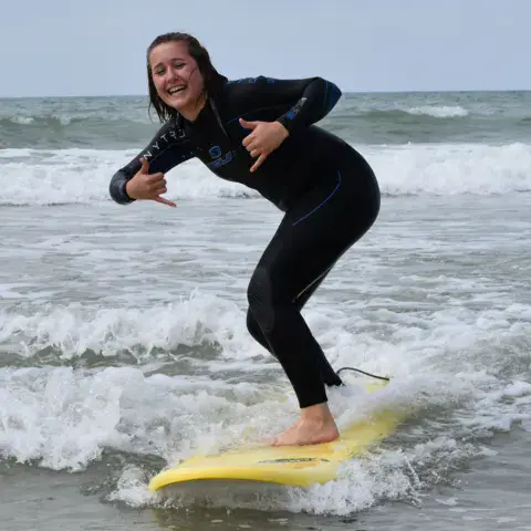 Élève debout sur une planche jaune pendant un cours de surf