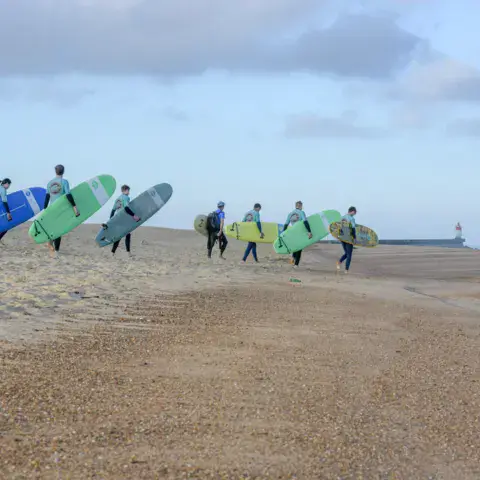 Groupe d'élèves avec leurs planches sur la plage