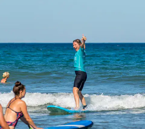 Surfeuse debout sur sa planche dans les vagues