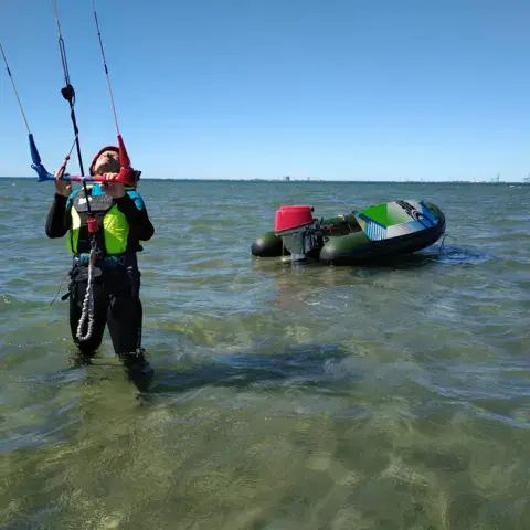 Élève kitesurf dans l'eau peu profonde de la baie