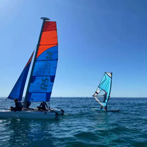 Catamaran et planche à voile en mer