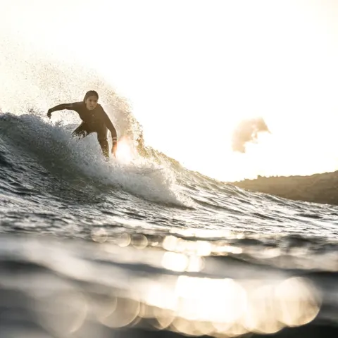 Surfeur sur une vague au coucher du soleil