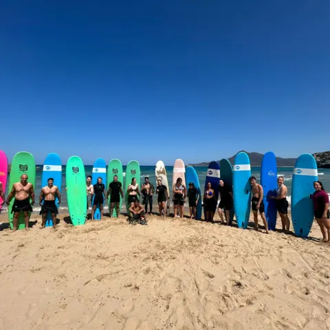 Groupe d'élèves avec leurs planches sur la plage