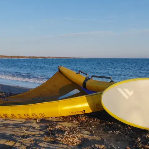 Ailes et planche de kitesurf posées sur la plage