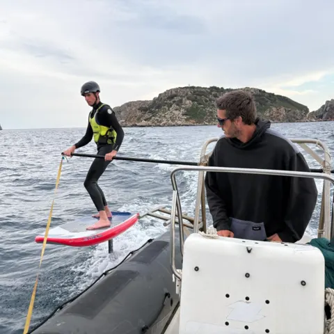 Élève en wingfoil suivi depuis un bateau