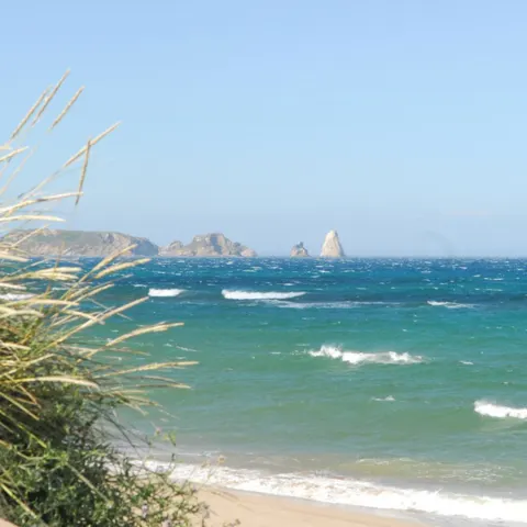 Plage de dunes et mer agitée, îles au loin
