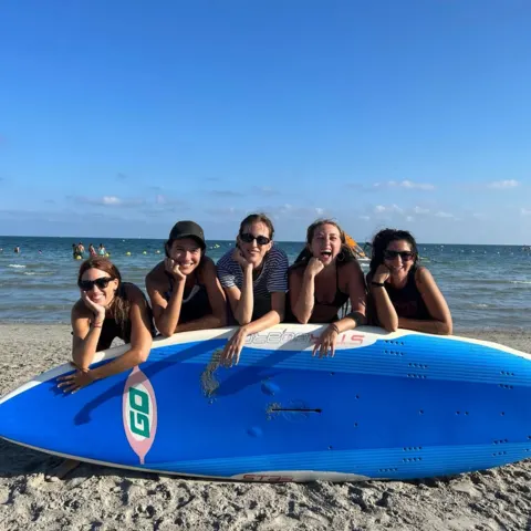 Groupe sur la plage derrière un paddle gonflable