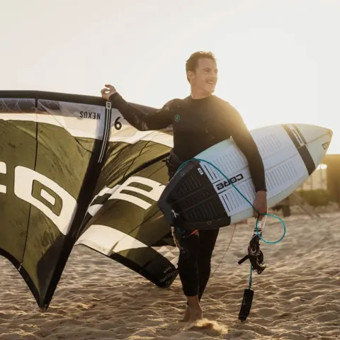 Kitesurfeur sur la plage avec son aile et sa planche