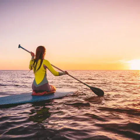 Pratiquante de paddle surf face au coucher du soleil