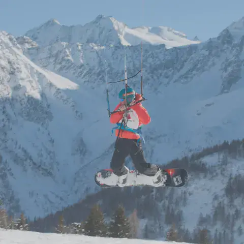 Snowkiter en vol sur snowboard au-dessus de la neige