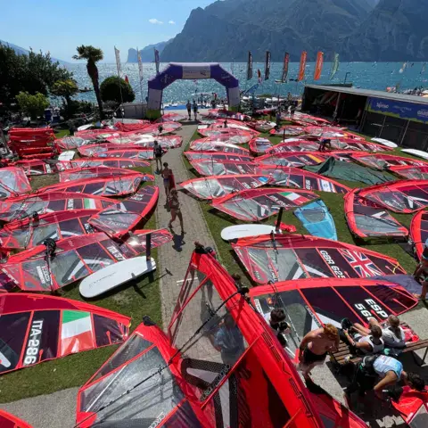 Voiles de windsurf déployées sur la pelouse du club avant une régate