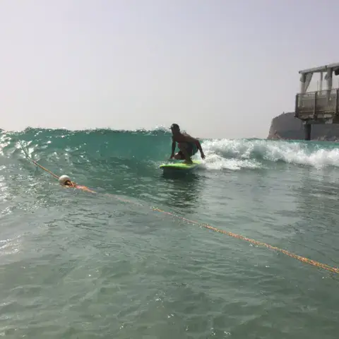 Surfeur sur une vague devant la plage du Poetto