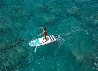 Pratiquante de stand up paddle en eau turquoise