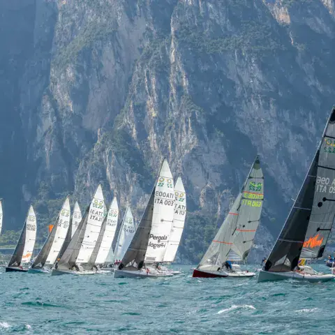 Flotte de voiliers en régate au pied des montagnes