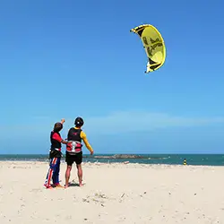 Briefing de kitesurf sur une plage de sable, aile dans le ciel