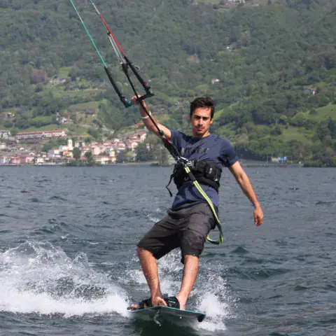Kitesurfeur sur sa planche avec un village en arrière-plan
