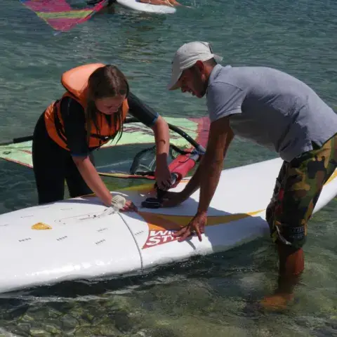 Moniteur et élève préparant une planche en bord de plage