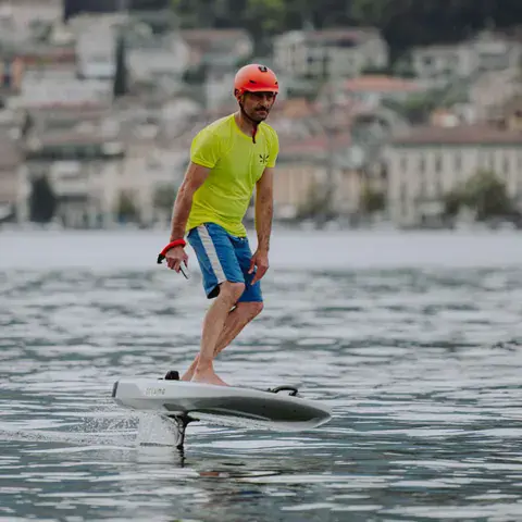 Rider en e-foil devant une ville du lac