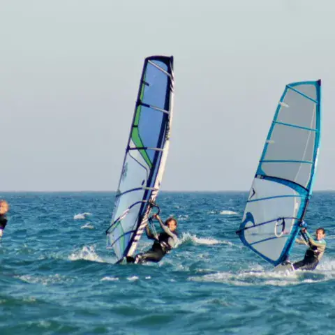 Trois windsurfeurs en navigation
