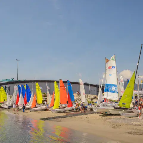 Voiles et dériveurs sur la plage du club