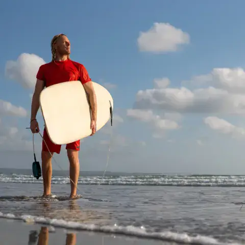Surfeur avec sa planche sur la plage