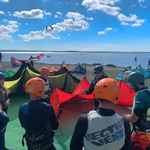 Groupe d'élèves équipés lors d'un cours de kitesurf