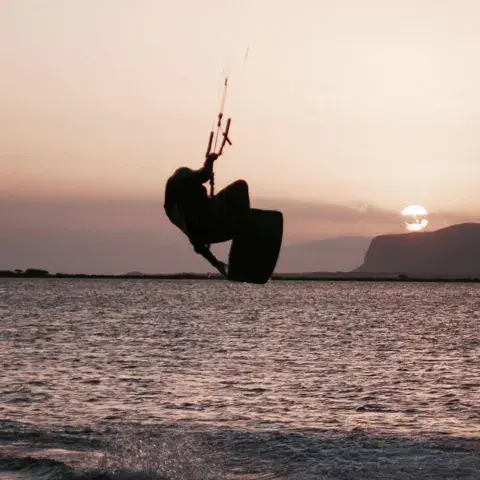 Saut de kitesurf à contre-jour au coucher du soleil