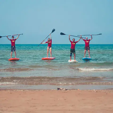 Groupe de stand up paddle dans l'eau peu profonde