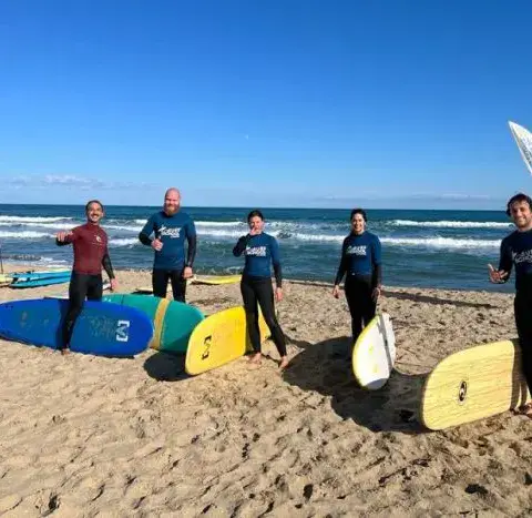 Groupe d'élèves et moniteurs sur la plage avec des planches