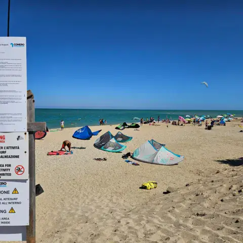 La plage avec le panneau d'information du spot