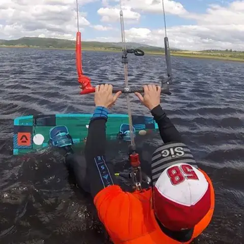 Kitesurfeur dans l'eau, barre en main