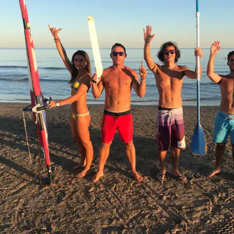 Équipe sur la plage avec planche de windsurf et pagaies