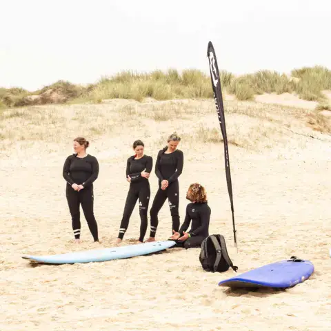 Élèves avec leurs combinaisons sur la plage de dunes
