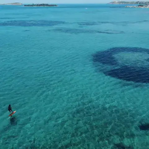Plan d'eau turquoise avec une aile de kite au loin
