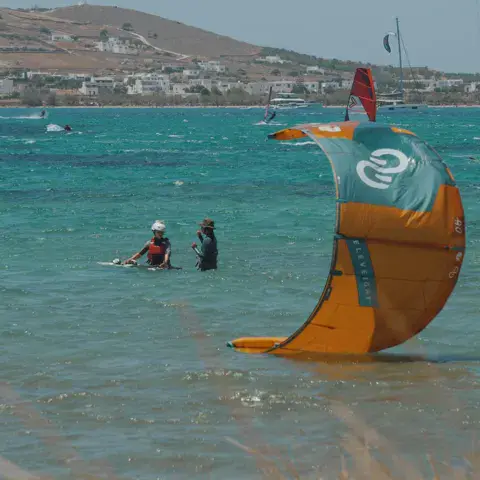 Aile de kite posée dans l'eau peu profonde, deux personnes à proximité