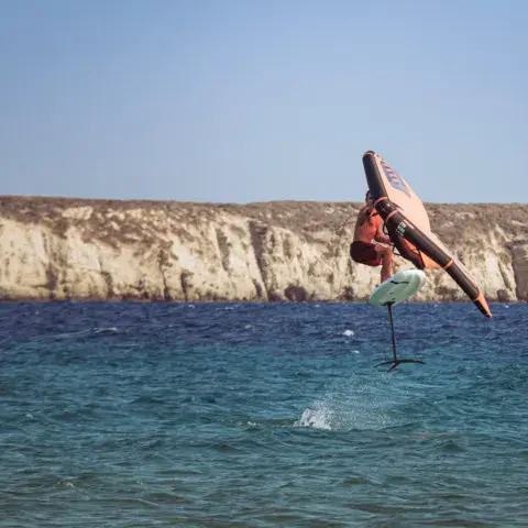 Rider de wingfoil en vol devant une falaise