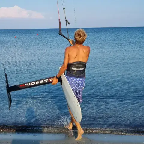 Rider portant sa planche foil vers l'eau