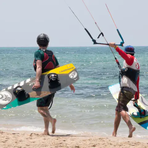Deux kitesurfeurs marchant sur la plage avec leur planche