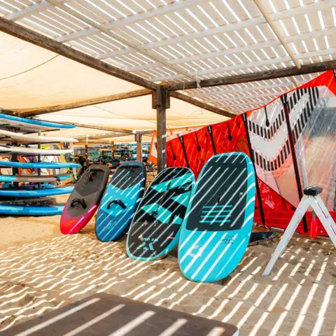 Planches et voiles de windsurf alignées sur le sable