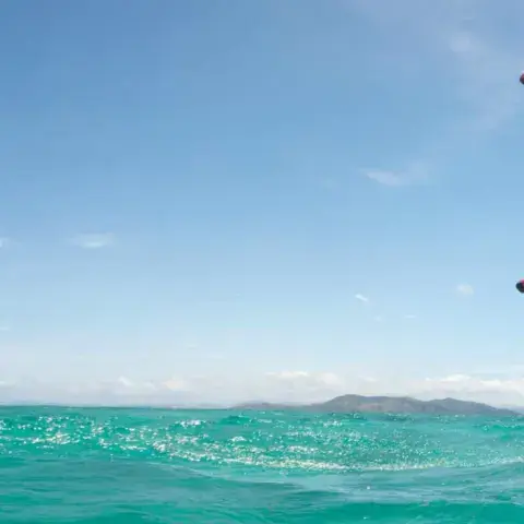 Rider en wing foil sur une eau turquoise