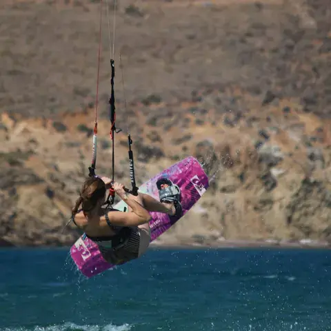 Kitesurfeur en saut au-dessus de l'eau devant une côte rocheuse