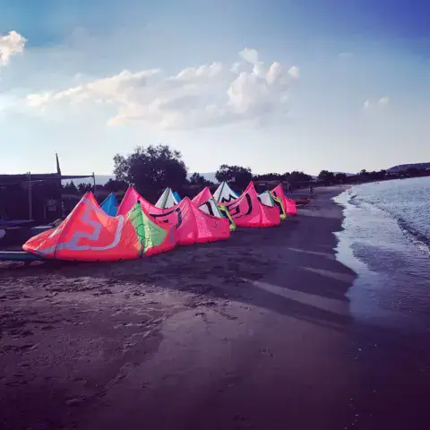 Ailes de kite gonflées alignées sur la plage au coucher du soleil