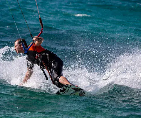 Kitesurfeur en navigation, gerbe d'eau derrière la planche