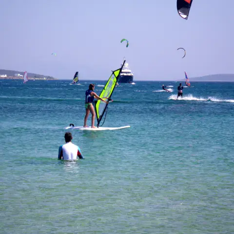Windsurfeurs sur une eau calme, kites dans le ciel