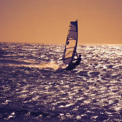 Windsurfeur en navigation au coucher du soleil