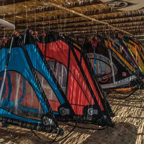 Voiles de windsurf colorées sous la toiture en roseaux