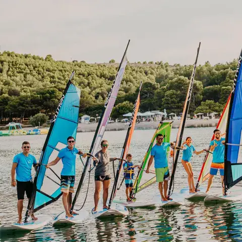 Élèves alignés avec leurs voiles dans l'eau peu profonde